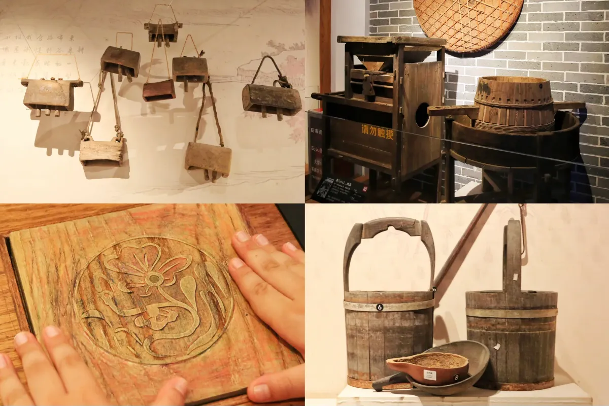 Museum display of traditional Chinese farming tools — wooden threshing implements, winnowing machines, and carrying buckets