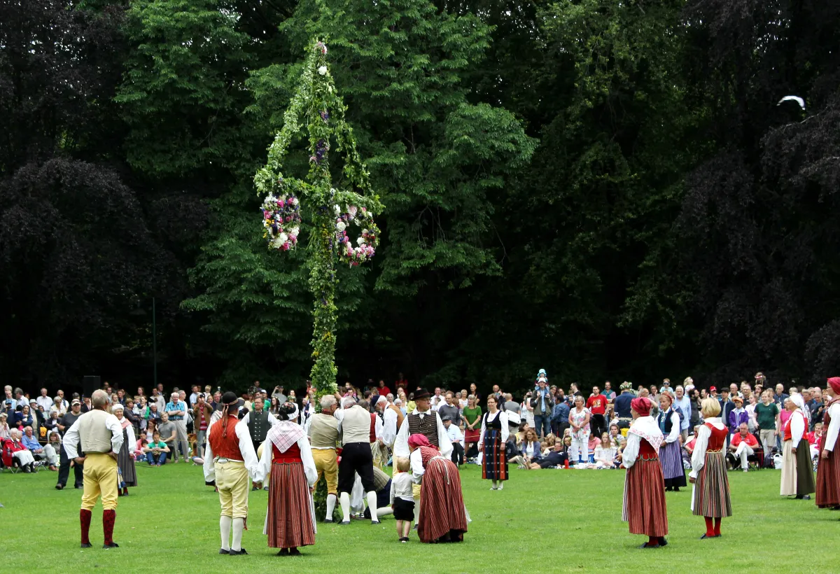 Dancing around the midsommarstång maypole — Swedish midsummer celebration in a flower-decorated meadow